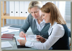 Two office workers looking over a spreadsheet